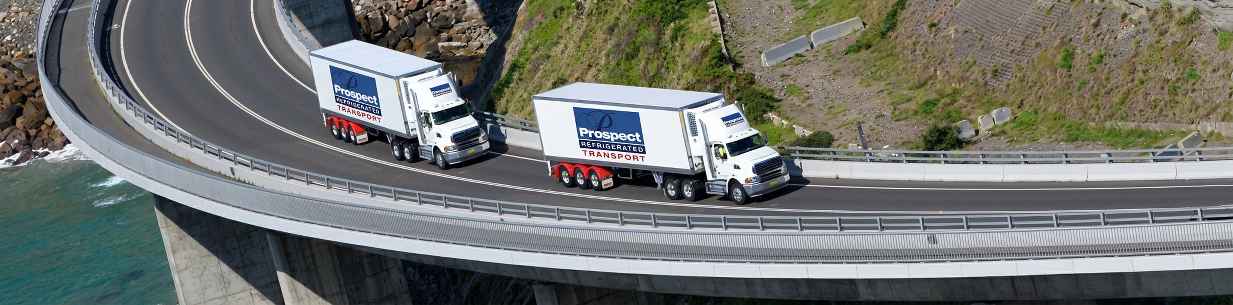 Two refrigerated trucks on Sea Cliff Bridge coastal highway